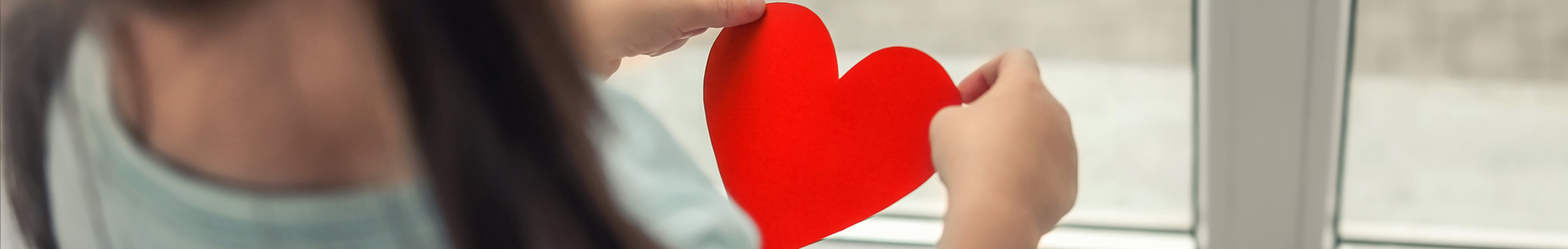 Little girl holding a red paper heart