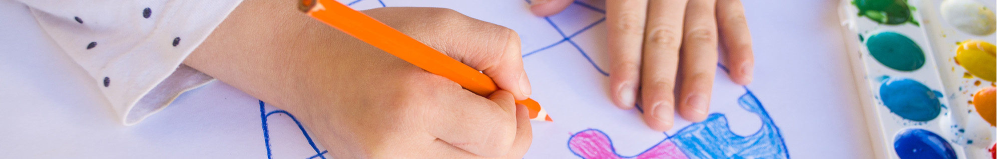 Young student coloring in a heart with colored pencils and paint