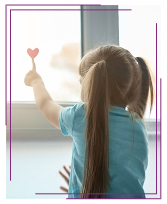 Little girl looking out the window with a heart