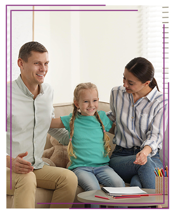 A young happy girl sitting on a couch with her parents